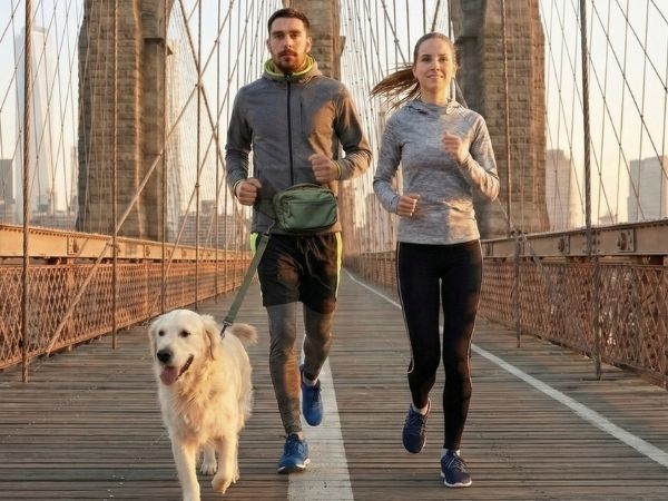 Couple running with dog wearing SUSU Grab & Go waist pack at Brooklyn Bridge