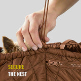 Hand tightening brown pet carrier sling with small dog's ears visible inside.