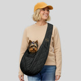 Woman wearing black quilted dog carrier sling with small dog inside