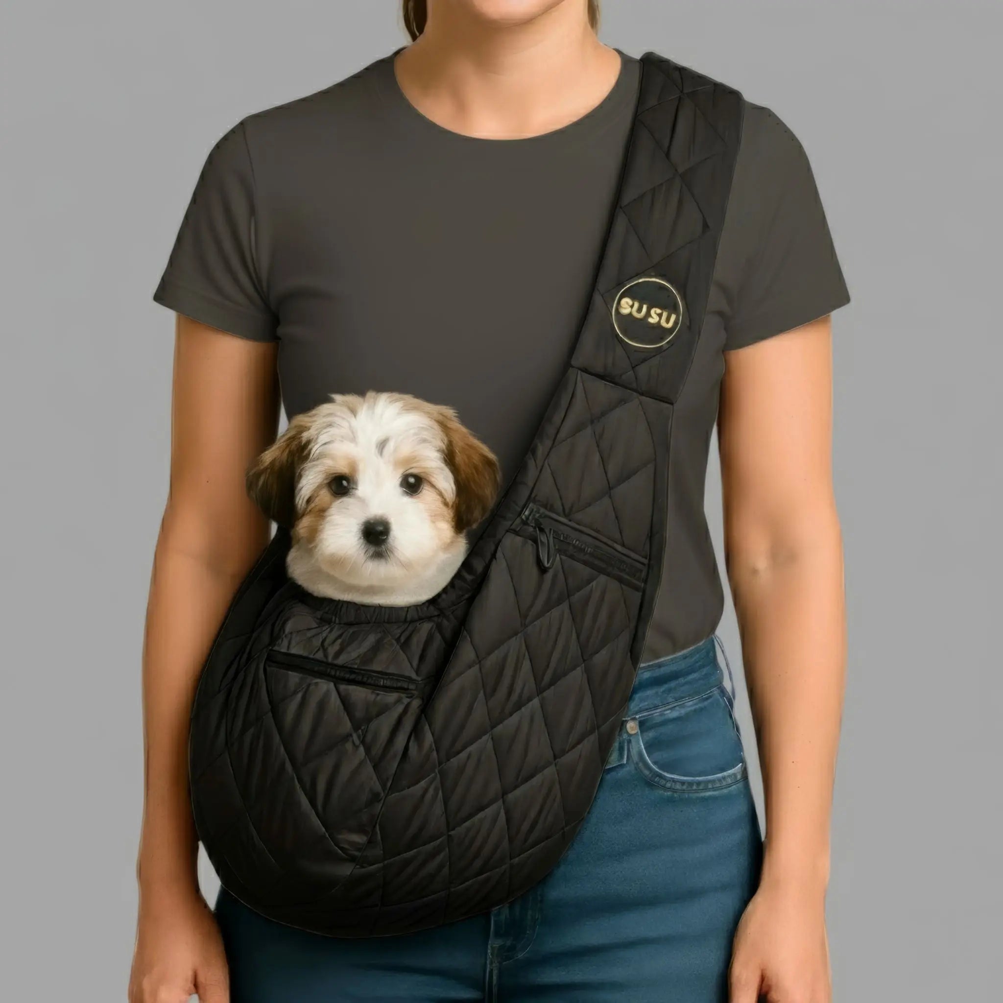 Woman walking in NYC wearing an olive green SUSU small dog carrier sling with a white pup snug in front, blurred city street and taxis behind