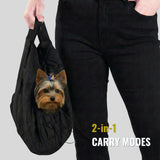 Small dog in black 2-in-1 pet carrier sling bag, person holding handle, text '2-in-1 carry modes'.
