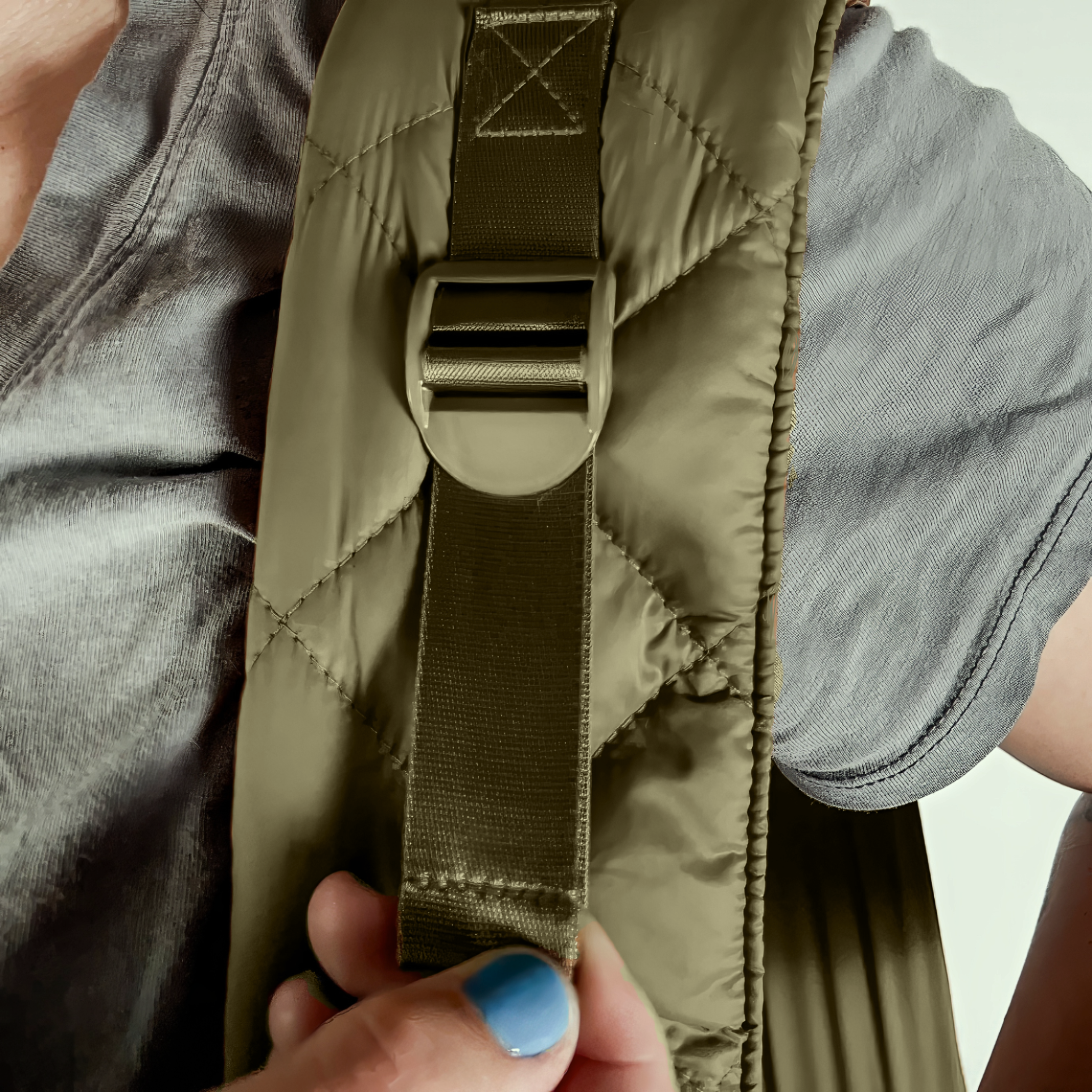 Close-up of a person adjusting the shoulder strap on the black SUSU Sling small dog carrier