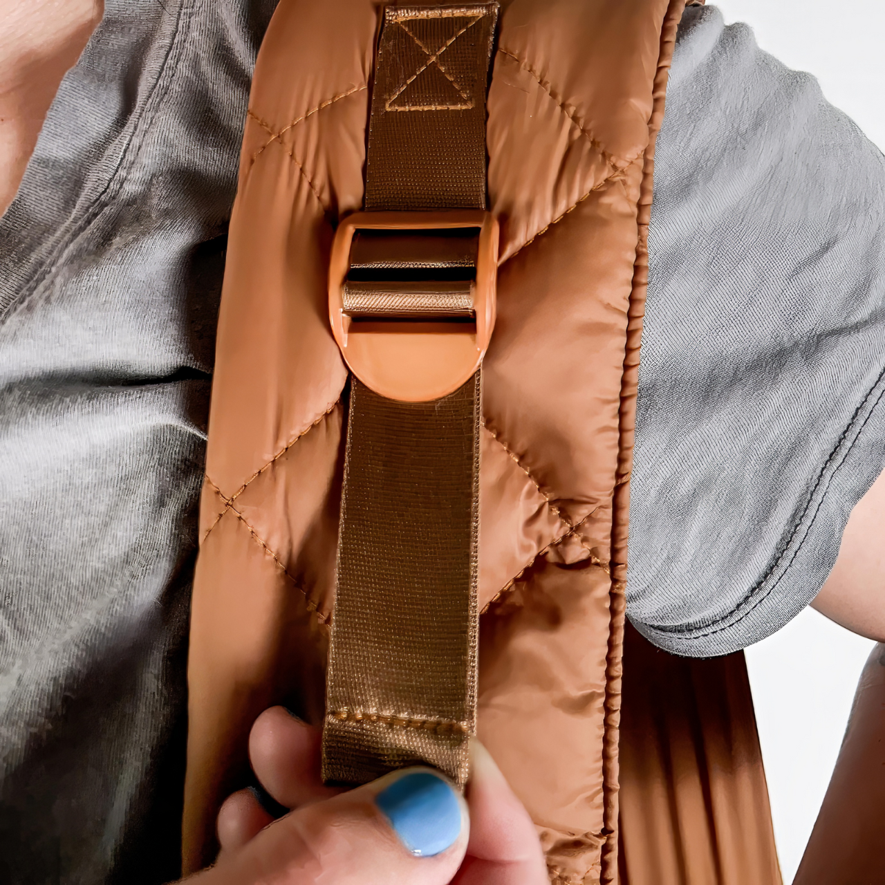 Close-up of a person adjusting the shoulder strap on the black SUSU Sling small dog carrier